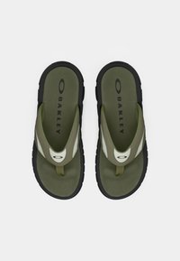Chanclas de color verde oliva con suelas de goma negra y detalles en blanco. Presentan un separador para los dedos y la marca 'OAKLEY' en la plantilla.