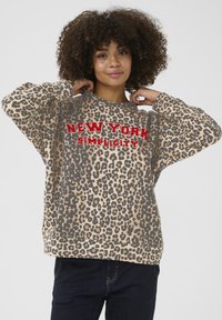 Mikina s leopardím vzorom v béžovej farbe, s červeným textom "NEW YORK SIMPLICITY". Voľný strih s okrúhlym výstrihom a dlhými rukávmi.