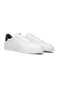 Witte leren sneakers met een gladde textuur, voorzien van een zwarte hielaccent en veters. Versierd met subtiele stiksels en logo details.