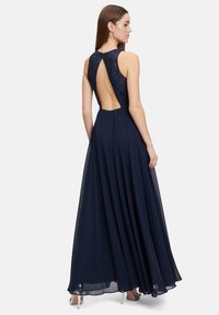 Navyblaue lange Kleid mit einem Spitzenrücken, ärmellosem Design und einem voluminösen, fließenden Rock mit Falten. Der Rückenausschnitt sorgt für zusätzliche Attraktivität.
