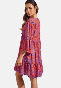 Kleurvolle, gemusterde jurk met felle oranje en paarse bloemdesigns, losse pasvorm, gerimpelde mouwen en gelaagde rok.