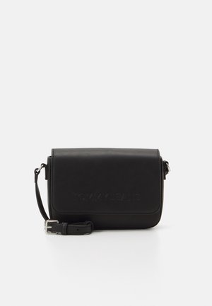 Czarna torba na ramię wykonana z materiału syntetycznego, z klapą zamykaną na zatrzask i wytłoczonym logo "TOMMY JEANS", z regulowanym paskiem.