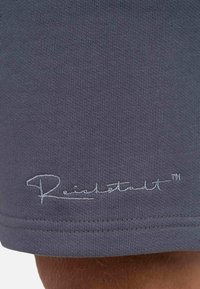 Grijze stoffen shorts met een gestructureerde afwerking. Beschikt over een gestikt logo in lichtgrijs aan de zoom. Eenvoudig ontwerp, slim fit en strakke lijnen.