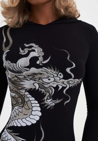 Schwarze Rippensweatjacke mit einem großen, detaillierten Drachendesign in Silber und Weiß, das Schuppen und fließende Linien zeigt.