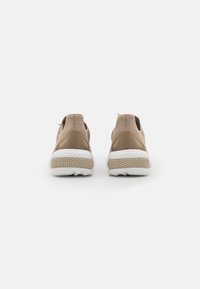 Scarpe sportive beige con tomaia in morbido tessuto a maglia, aperture elastiche e suole in gomma bianca dotate di un motivo di battistrada testurizzato.