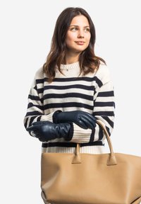 Black leather gloves, cream and navy striped sweater, holding a large tan leather bag. Smooth texture and structured design.