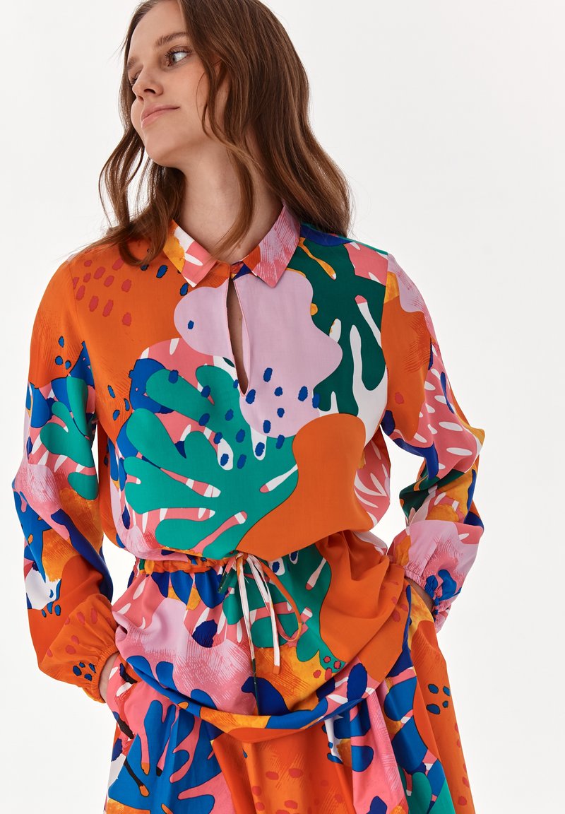 Färggjort, mönstrat skjorta med krage, som har abstrakta mönster i grönt, rosa och orange, samt en insydd midja med dragsko.