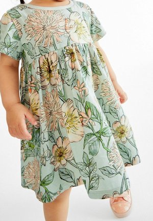 Robe florale bleu clair à manches courtes. Présente de grandes fleurs pastel et des feuilles vertes, une taille froncée et une texture douce.