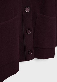Tmavo purpurový cardigan s textúrovanou tkaninou, štyrmi zodpovedajúcimi gombíkmi a dvomi prednými vreckami. Okraje sú jednoduché s jemným zakončením.