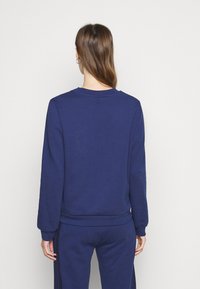 Tmavě modrá mikina s dlouhými rukávy, kulatým výstřihem a žebrovanými manžetami. Měkká tkanina s čistým, jednoduchým designem, bez viditelných vzorů nebo log.