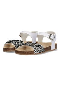 Witte sandalen met zwart-witte gevlekte banden, een plat kurken zool en een verstelbare gesp. Zachte binnenvoering en open teen ontwerp.