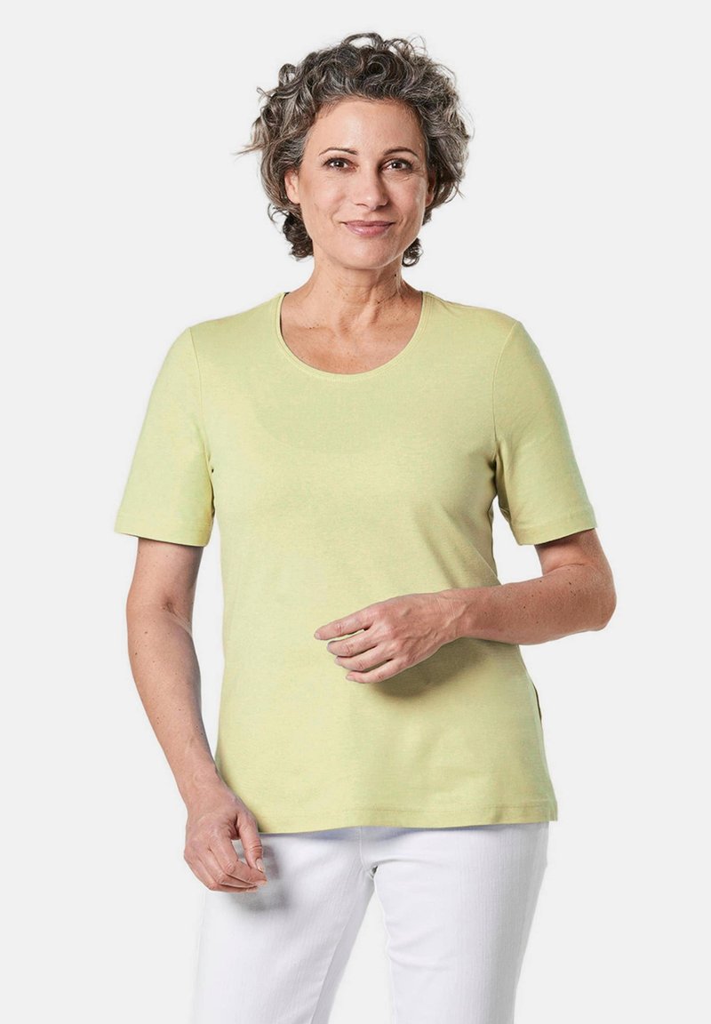 Hellgrünes T-Shirt mit kurzen Ärmeln und rundem Halsausschnitt, aus weichem Material, mit geradem Schnitt und seitlichen Schlitzen für Bewegungsfreiheit.