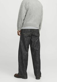 Mörk denimjeans med lös passform, raka ben, minimal blekning och två bakfickor. Kombineras med en grå stickad tröja.