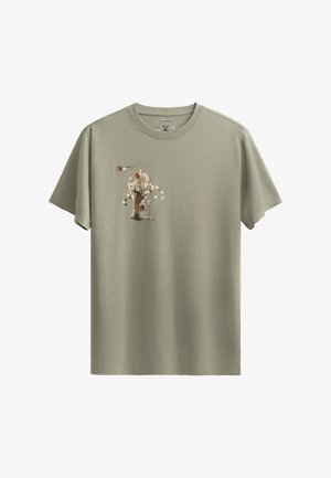 Olijfgroene katoenen t-shirt met een grafische print op de borst, voorzien van geometrische patronen en een gestileerde figuurillustratie.