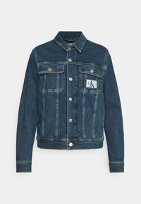 Tmavě modrá džínová bunda s knoflíkovým zapínáním, dvěma náprsními kapsami a logem na levé kapse. Klasický límec a dlouhé rukávy.