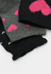 Drei Paar Socken: schwarz mit kleinen silbernen Punkten, grau mit pinken Herzen und dunkelgrau mit großen pinken Herzen. Weiche Stricktextur, dehnbarem Stoff.