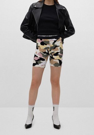 Shorts de cycliste à motif camouflage aux tons beige, rose et noir ; associés à un haut noir ajusté et une veste en cuir.