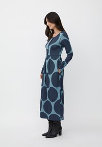 Abito a maniche lunghe, di lunghezza media, con cerchi blu e teal, realizzato in morbido cotone misto, con tasche laterali e chiusura frontale con bottoni.
