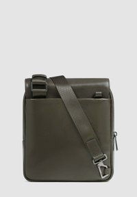 Borsa a tracolla in pelle verde oliva con tracolla regolabile, texture liscia, tasca laterale con zip e dettagli in metallo. Forma quadrata.