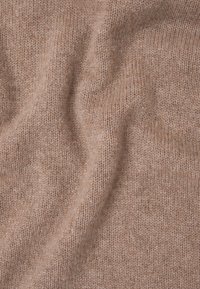 Tessuto di maglia marrone chiaro con una consistenza morbida e motivi intrecciati visibili, caratterizzato da leggere variazioni di tonalità in tutto il materiale.