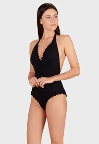 Svart baddräkt med djup V-ringning, volangkanter, halterneck-design och slät textur, lämplig för strand- eller poolanvändning.