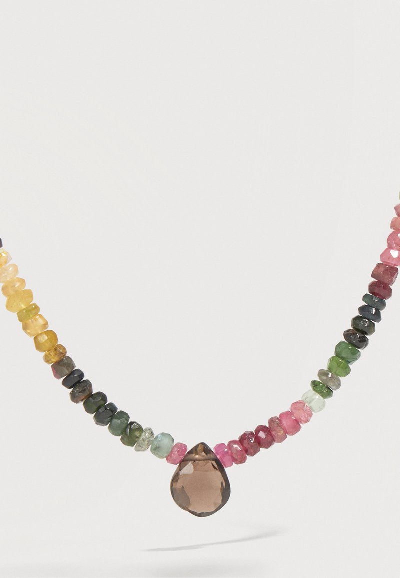 Collier de perles facettées multicolores avec un grand pendentif marron en forme de goutte au centre sur un fond clair.