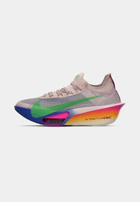 Jasno beżowy but sportowy o teksturowanej powierzchni, z zielonym akcentem, tęczową gradientową podeszwą, półprzezroczystymi detalami oraz napisem "Żaden człowiek nie jest ograniczony".