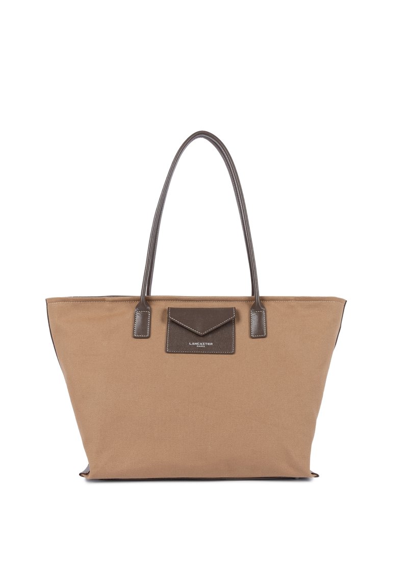 Grand sac fourre-tout en toile beige avec poignées en cuir brun foncé et poche avant, marque Lancaster Paris sur le rabat de la poche.