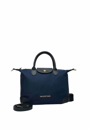 Sac à main Valentino bleu marine avec poignées en cuir noir, logo doré, fermeture à rabat et bandoulière amovible enroulée à côté du sac.