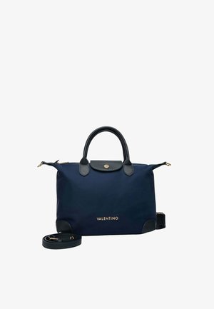 Sac à main Valentino bleu marine avec poignées en cuir noir, logo doré, fermeture à rabat et bandoulière amovible enroulée à côté du sac.