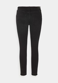 Černé skinny džíny s hladkou texturou, které mají dvě zadní kapsy a roztrhané lemy. Design zahrnuje střední pas a žádné viditelné kovové doplňky.