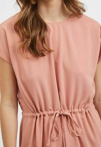 Růžové, lehké a splývavé šaty s krátkými rukávy a kulatým výstřihem. Mají šňůrku v pase pro nastavitelný střih. Hladká textura.