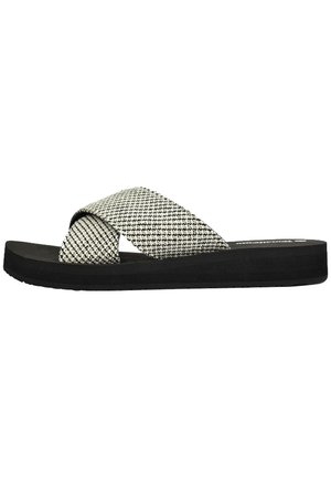 Sandalias deslizantes en blanco y negro con tiras trenzadas en cruz y una superficie texturizada, que cuentan con una suela de goma plana. Sin detalles de herrajes visibles.