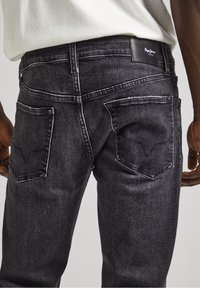 Mörkgrå jeans i denim, med en klassisk femficksdesign, kontrasterande sömmar och en läderetikett i midjan.