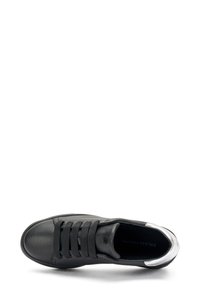 Baskets en cuir noir avec garniture argentée, présentant des lacets élastiques, un bout rond et une finition texturée sur la tige. Semelle en caoutchouc plate.