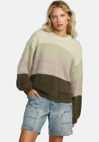 Vezelige gebreide trui in crèmekleur, groen, roze en donkergroene strepen. Ronde halslijn, losse pasvorm en textured materiaal. Gecombineerd met denim shorts.