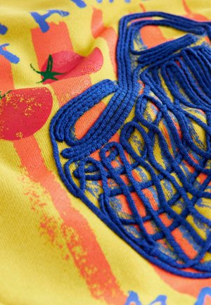 Geel stof heeft een blauw geborduurd ontwerp dat lijkt op een net, met rode tomaatafbeeldingen en oranje strepen, wat een textuureffect creëert.