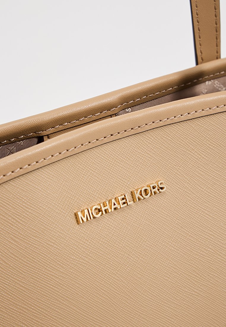 Borsa sintetica beige con finiture texture e logo dorato "MICHAEL KORS". Presenta manici doppi e un design strutturato.