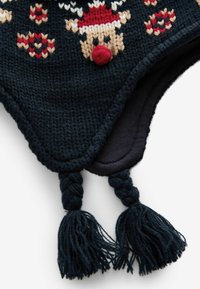 Chapeau tricoté bleu foncé avec des motifs festifs, doté d'un pompon rouge et de glands tressés. Texture douce, design chaud et motifs ludiques.