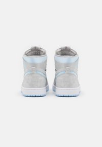 Zapatillas altas de ante gris claro con acentos en azul, que cuentan con un collarín acolchado, interior texturizado y suela de goma blanca.