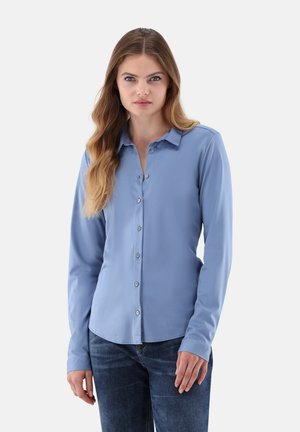 Hellblaues Langarmhemd mit Knopfleiste, klassischem Kragen, glatter Textur und abgerundetem Saum, kombiniert mit dunklen Jeans.