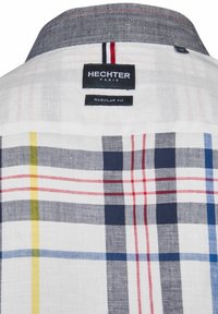 Weiß kariertes Hemd mit blauen, roten, gelben und grauen Karomustern. Hervorgehoben durch einen grauen Kragen mit kontrastierenden Nähten und Markentags.
