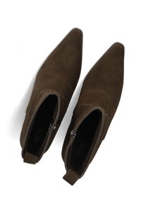 Bruine suedine enkelboots met puntige neuzen, zijritsen en trekloops. Soepele textuur en minimalistisch ontwerp. Zwarte zolen zichtbaar.