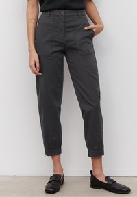 Tummanharmaat, lyhyet housut, joissa on kapea malli, joustavat hihansuut, etutaskut ja napitus. Valmistettu sileästä kankaasta.