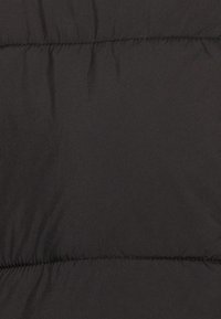 Tissu noir matelassé avec des coutures horizontales créant des sections rembourrées, suggérant un matériau pour une veste ou une couverture chaude.