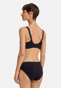 Černá bezdrátová podprsenka a odpovídající kalhotky s vysokým pasem vyrobené z hladké tkaniny, s nastavitelnými ramínky a minimálním kovovým příslušenstvím pro elegantní vzhled.