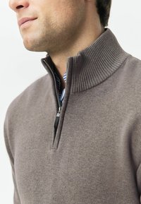 Pulover tricotat de culoare gri, cu guler ribat și fermoar pe jumătate. Prezintă o textură netedă și un strat interior cu dungi albastre și albe.