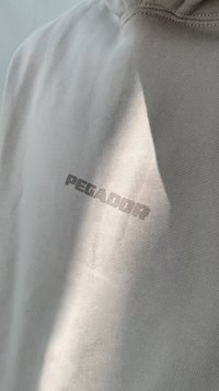 Γκρι φούτερ σε ανοιχτό τόνο με απαλή υφή και ανασηκωμένο λογότυπο "PEGADOR" σε σκουρότερο απόχρωση. Απλός σχεδιασμός με κανονική εφαρμογή και λαιμό.