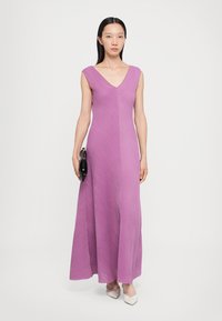 Pikk, ilma varrukat Kleid lavendlis sügava V-dekolteega. Omab tekstureeritud, volditud disaini. Kaunistatud musta portfelliga ja heledate kingadega.