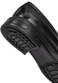 Zapato negro sin cordones con un upper de cuero liso y brillante, suela de goma resistente con un patrón de textura para mayor agarre.